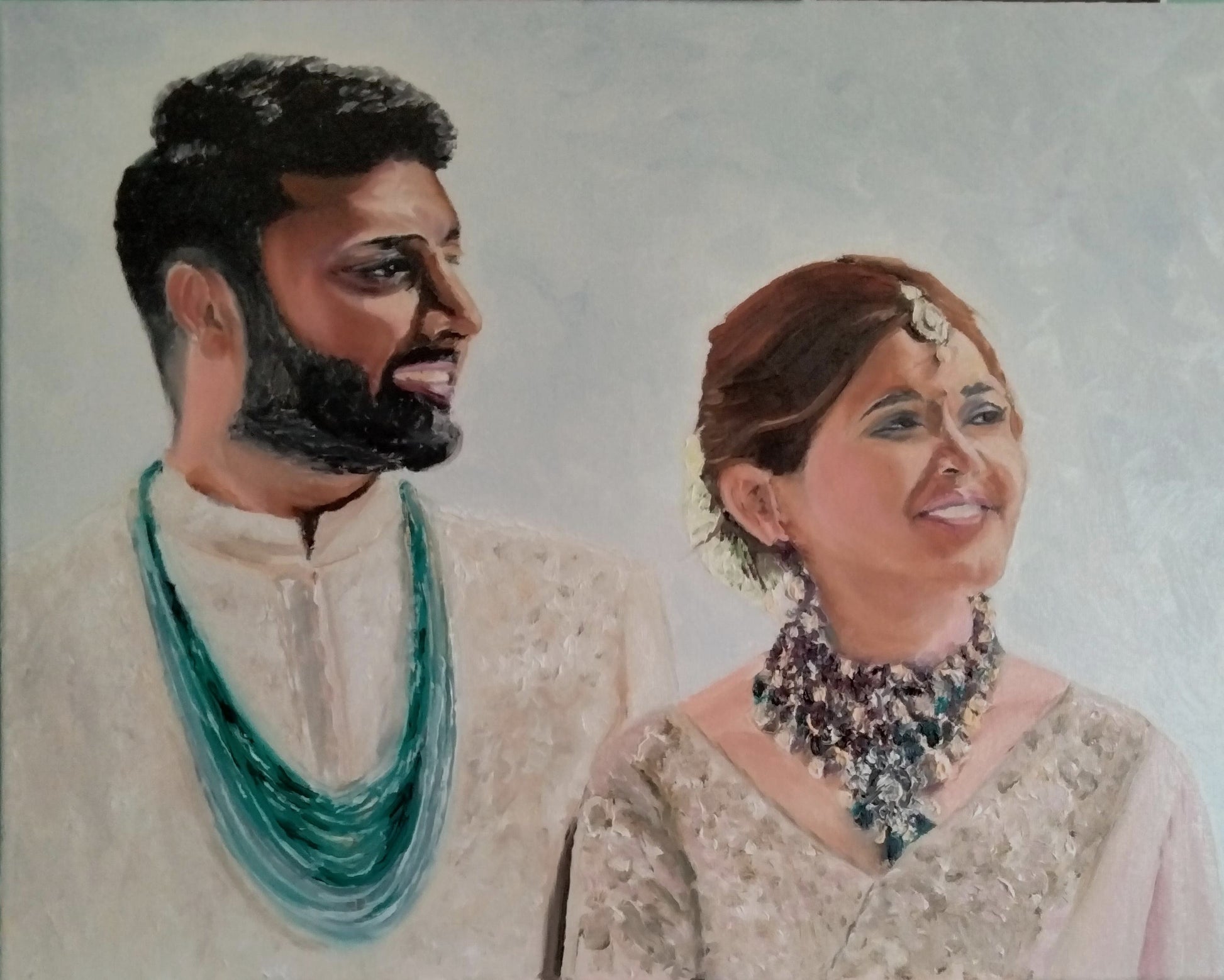 Double profile portrait of an Indian bride and groom, in traditional Indian attire, looking happy.